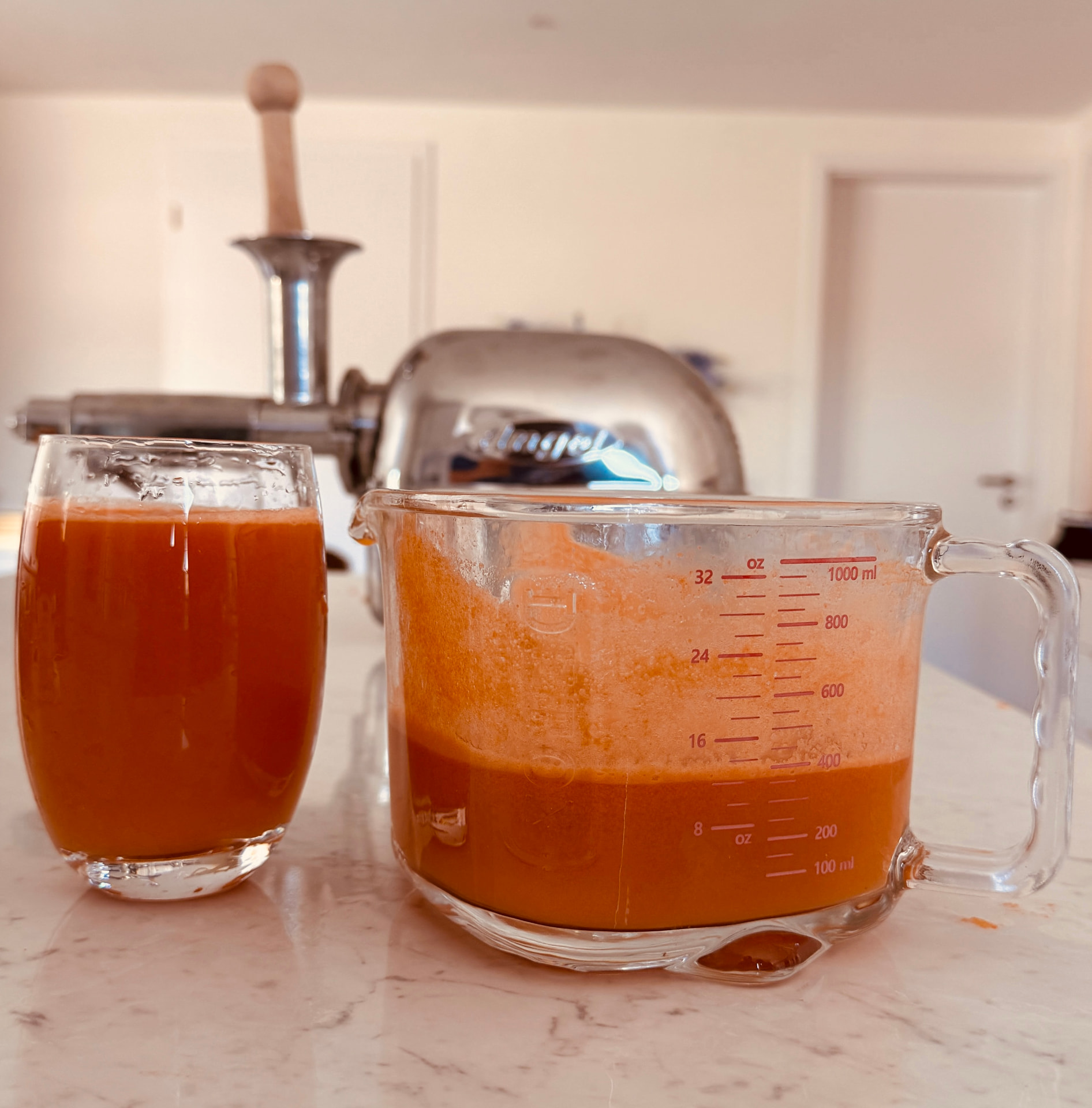 Glas und Messbecher mit orangefarbenem Saft vor dem Angel Juicer 7500
